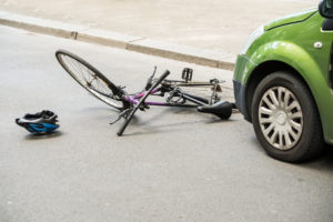 A ruined bike lying on the ground in front of a car before a person calls a bicycle-accident-lawyer-Roseland-NJ